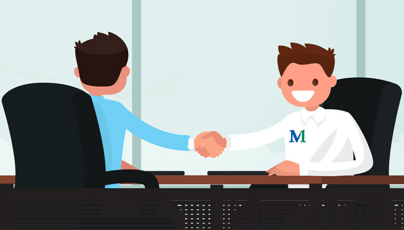 M1 Credit Union coworkers engaged in a discussion at a desk, highlighting mentorship, collaboration, and career development opportunities in a supportive workplace.