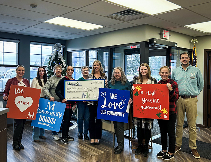 M1 Credit Union staff and Alma community members gathered in the branch lobby celebrating the Community Bonus event with smiles and local engagement.